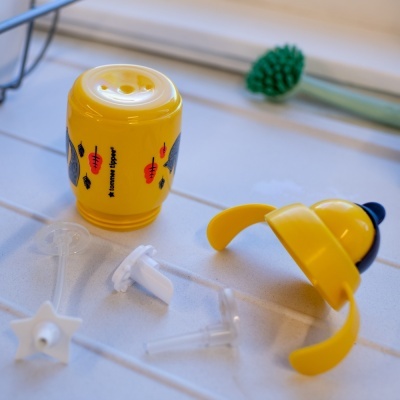 Copo infantil amarelo com desenhos de cenouras e acessórios transparentes em superfície branca