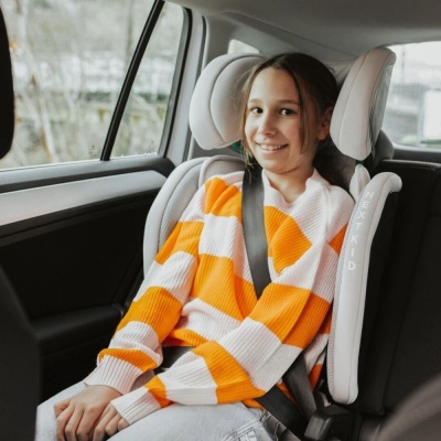 Criança sentada em assento elevatório infantil NEXT KID cinzento claro dentro de carro