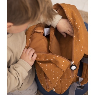 Mochila castanha de tecido com padrão branco e fecho de correr, mãos de criança manuseando-a