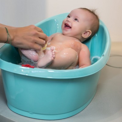 Bebé numa banheira azul-turquesa a ser lavado