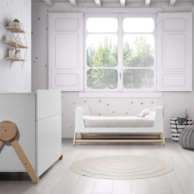 Quarto de bebé com berço branco, tapete redondo creme e decoração de estrelas douradas na parede