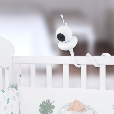 Câmara de vigilância branca numa grade de berço com roupa de cama estampada