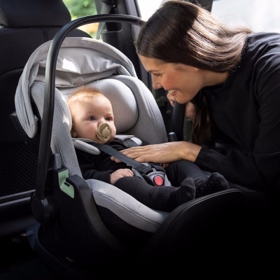 Cadeira auto cinzenta para bebé com interior acolchoado e cinto de segurança a preto com fecho vermelho