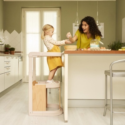 Criança em banco-escada de madeira na cozinha