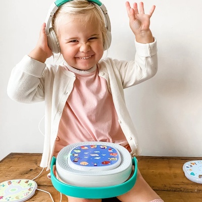 Menina com auscultadores e leitor de música portátil colorido sentado numa cadeira de madeira