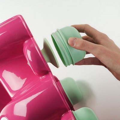 Suporte rosa com ventosas verdes e mão a afixar uma ventosa