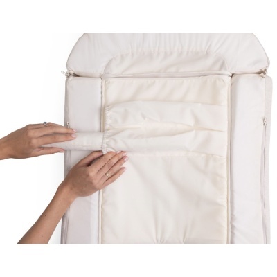 Colchão de bebé branco acolchoado com mãos a ajustar almofada