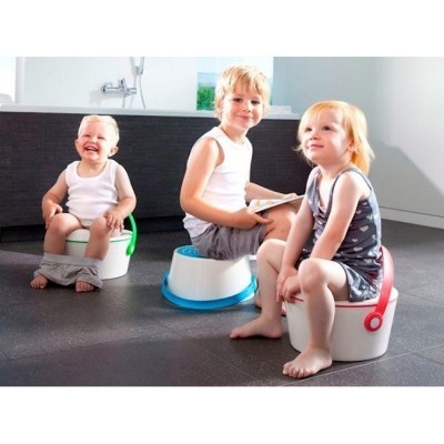 Três crianças sentadas em penicos de plástico em casa de banho