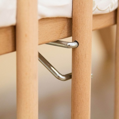 Detalhe de estrutura de berço de madeira com suporte metálico prateado