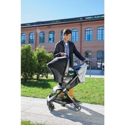 Carrinho de bebé preto e cinza com homem a empurrar ao ar livre