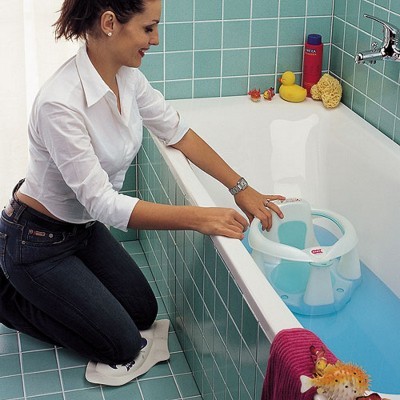 Assento de banho infantil azul e branco na banheira com mulher ajoelhada a mexer no assento