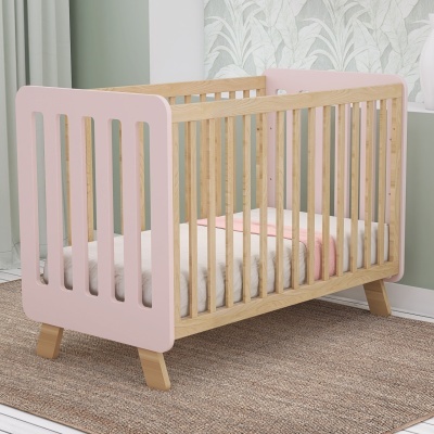 Berço de bebé de madeira com laterais cor-de-rosa e colchão branco com manta rosa