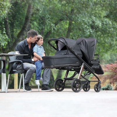 Carrinho de bebé preto com homem e criança sentados em ambiente exterior