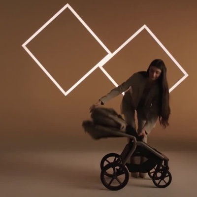 Mulher empurra carrinho de bebé bege em cenário iluminado com formas geométricas