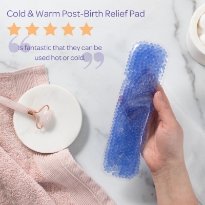 Cold & Warm Post-Birth Relief Pad azul com pequenas esferas, mão segurando, e acessórios de massagem cor-de-rosa sobre superfície branca.