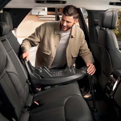 Homem a instalar uma base de cadeirinha para crianças num carro com interiores pretos