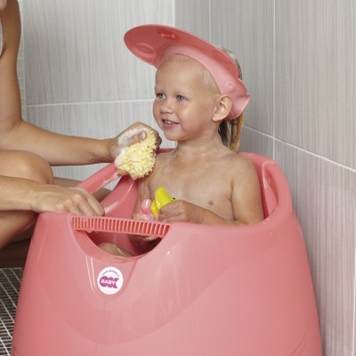 Bebé em banheira rosa a ser lavado com esponja amarela em casa de banho