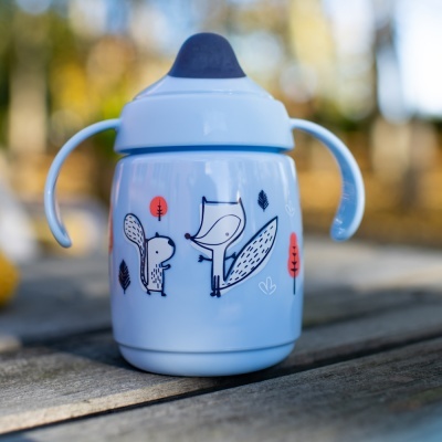 Copo de treino azul claro com desenho de esquilo e raposa em madeira ao ar livre