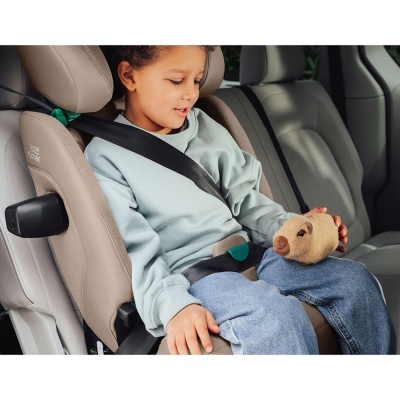 Criança em cadeira auto bege Britax Römer com cinto de segurança no banco traseiro do carro