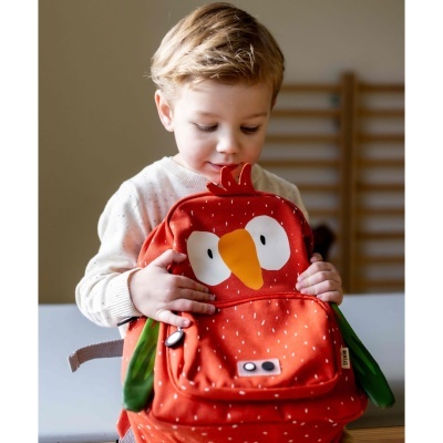 Criança segurando mochila infantil vermelha com desenho de ave.