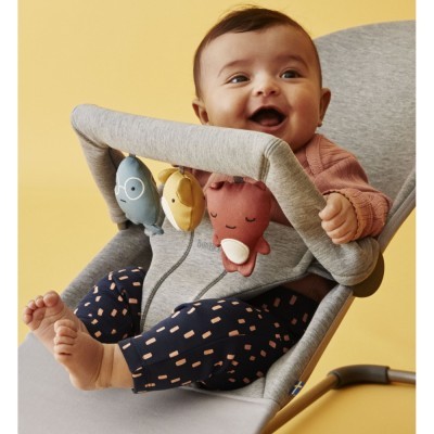 Bebé num assento cinzento com brinquedos coloridos pendurados