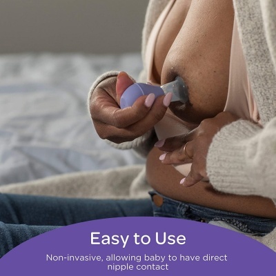 Bombinha extratora de leite de silicone roxa usada por mulher sentada na cama