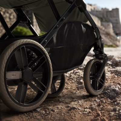 Carrinho de bebé com rodas grandes e tecido cinza-escuro sobre terra