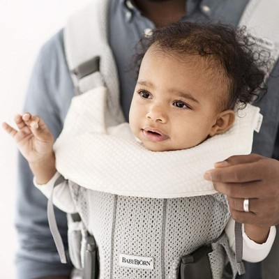 Bebé em porta-bebés cinzento BABYBJÖRN com almofada branca acolchoada