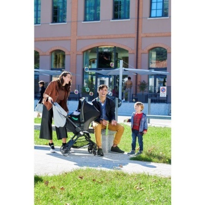 Carrinho de bebé preto com mulheres e crianças ao ar livre em parque urbano