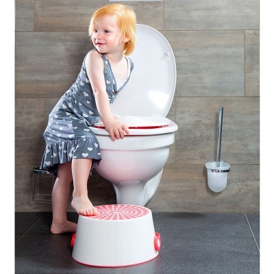 Criança junto a sanita com banquinho branco e detalhes vermelhos