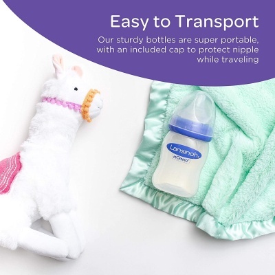 Mamadeira Lansinoh ao lado de fralda verde e brinquedo branco em formato de lhama