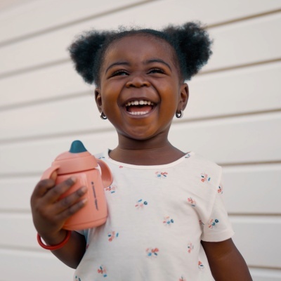 Menina com copo infantil cor de salmão e t-shirt branca com desenhos florais