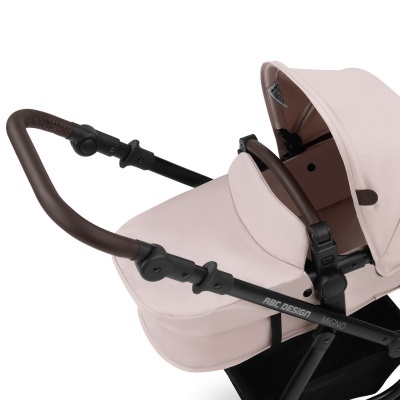 Carrinho de bebê rosa claro com estrutura preta e pega marrom escura