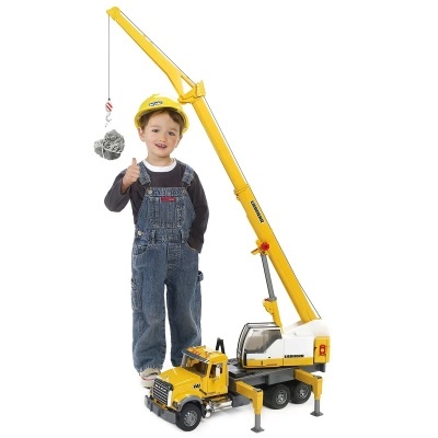 Criança com capacete junto a brinquedo de guindaste amarelo