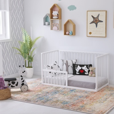 Berço infantil branco com almofadas e decoração em quarto de criança.