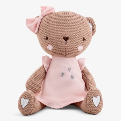 Urso de peluche castanho tricotado com vestido rosa e laço na cabeça.