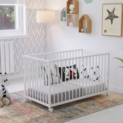 Berço branco em madeira com almofadas estampadas num quarto infantil decorado.