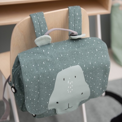 Mochila infantil verde com padrão de pontos brancos e rosto de urso, pendurada numa cadeira