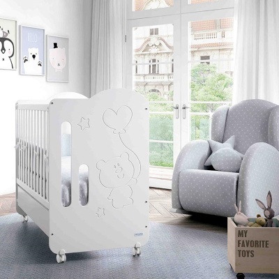 Berço branco de madeira com desenho de urso, poltrona cinzenta com estrelas e caixa de brinquedos em quarto