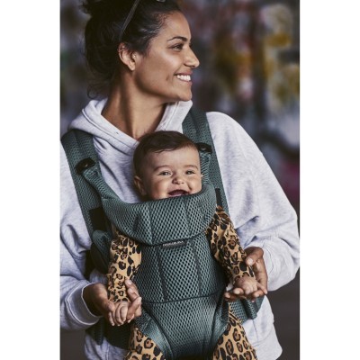 Mulher com porta-bebés verde e bebé com fato de leopardo