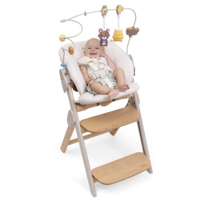 Bebé sentado em cadeira alta com assento almofadado creme e brinquedos pendurados