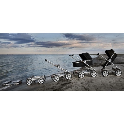 Quatro carrinhos de bebé em diferentes estados de montagem numa praia