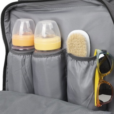 Interior de mochila cinzenta com biberões, escova e óculos de sol.