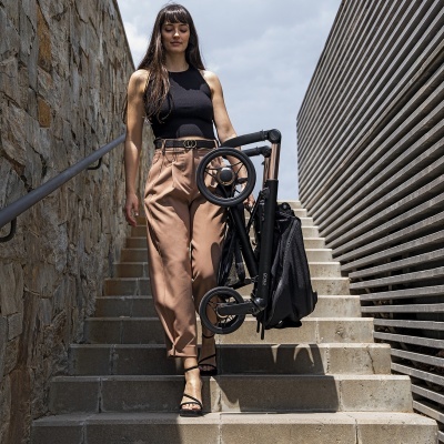 Mulher a descer escadas a carregar carrinho dobrável preto