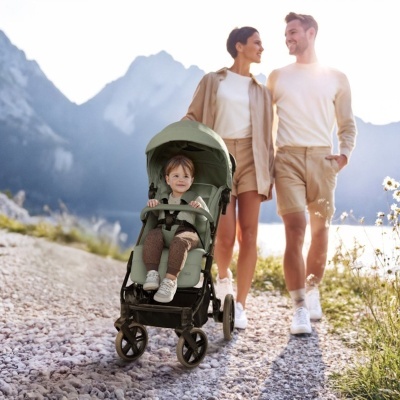Carrinho de bebé verde com criança e casal a caminhar em zona montanhosa