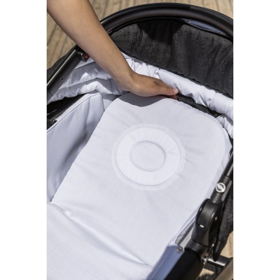 Carrinho de bebé preto com interior branco e almofada com padrão circular