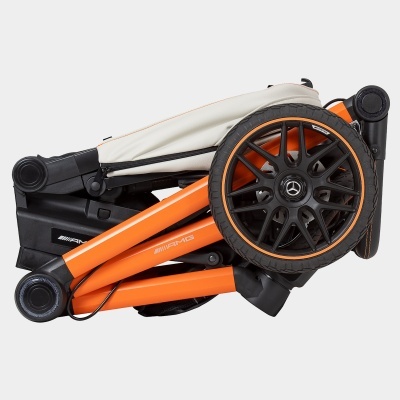 Carrinho de bebé dobrado com estrutura laranja e rodas pretas com detalhes laranja