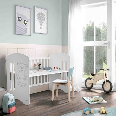 Quarto infantil com secretária, cadeira azul, quadros na parede, brinquedos no chão e bicicleta de madeira