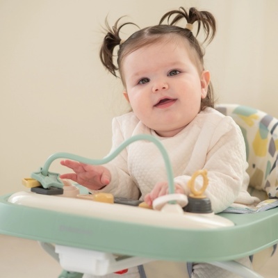 Bebé sentada num andador verde e branco com brinquedos