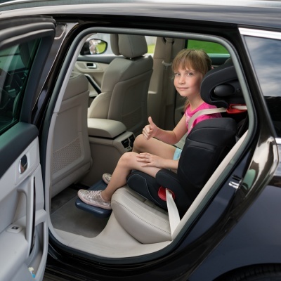 Cadeira auto preta com menina sentada no banco traseiro de carro